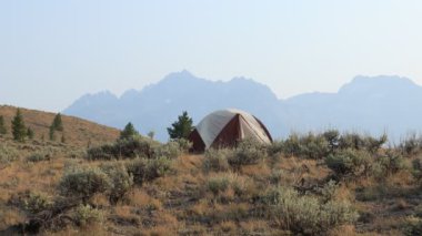 Custer County, Idaho 'daki Stanley kasabasının yakınlarındaki bir sagebrush' ın arasında yalnız bir kamp çadırı kurulmuştur. Sawtooth Mountain Range ve Williams Peak kulesi. Yaz mevsiminde, orman yangınları yüzünden havada biraz sis olur..