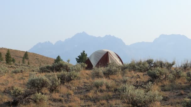 爱达荷州卡斯特县斯坦利市附近 一个孤独的露营帐篷被安顿在斑马丛中 锯齿山山脉和威廉姆斯峰塔顶在远处 夏天的时候 野火给空气蒙上了一层薄雾 — 图库视频影像