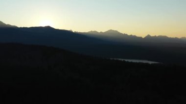 Sunset over the jagged peaks of the Sawtooth Mountains and Yellow Belly Lake in Idaho. Aerial shot leftwards tracking shot on a summer evening.