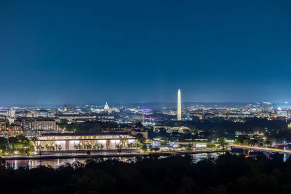 Potomac Nehri 'nin Virginia tarafından izlenen Washington D.C.' nin ikonik siluetini gösteren gece fotoğrafı. Çekim, aydınlatılmış Washington Anıtı ve ABD Kongre Binası 'nı vurguluyor. 