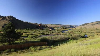 Stanley, Idaho 'da bir yaz öğleden sonrası. Valley Creek, yeşil çimlere yuva yapmış kulübelerin yanından akar. Etrafı el değmemiş dağ güzelleriyle çevrili huzurlu bir kaçış sunar..