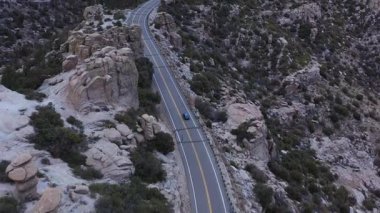 Alacakaranlıkta, Tucson, Arizona 'daki Lemmon Dağı' nın tepesine çıkan Catalina Otoyolu Sahne Yolu 'nda bir araba, kaya kabadayılarının yanından geçiyor..