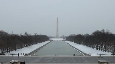 Washington Anıtı ve Yansıtıcı Havuz Washington, D.C. 'de bir kar fırtınası sırasında görüldü. İnsanlar anma törenini ziyaret etme cesaretini gösterdiler..