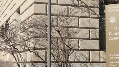 Washington, D.C. 'deki Milli Gelir İdaresi (IRS) merkezinin önünde bir bilgi işareti. Kamera görüntüsü soldan sağa döner.