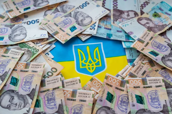 Ukrayna bayrağının arka planında Ukrayna para birimi Hryvnia. Ukrayna 'daki savaşla ilgili olarak vatandaşlara devlet yardımı.