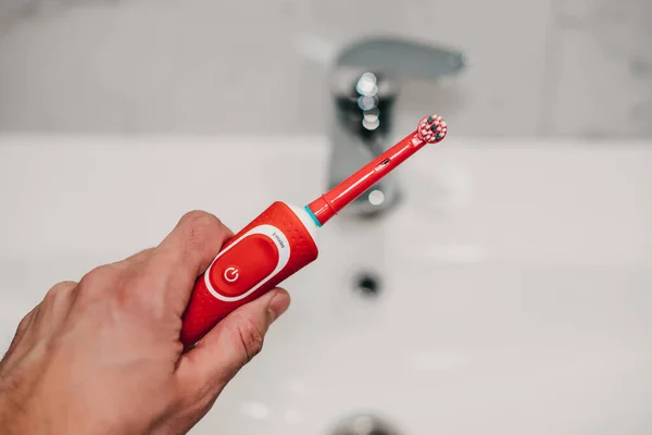 electric toothbrush in hand in the bathroom
