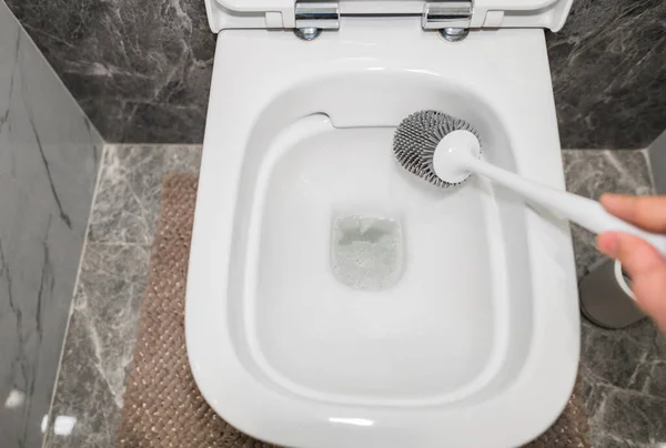 Washing the toilet with a gray silicone sponge