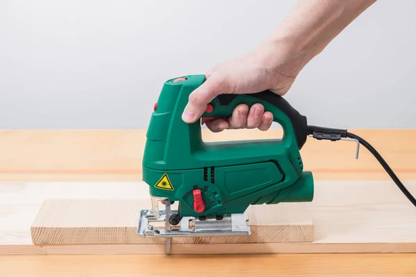 一个人带着电锯在木制桌子上干活 有的带手套 有的不带手套 有的带着胶带量尺寸 — 图库照片