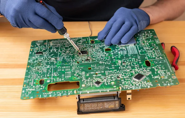 stock image A man holds a soldering iron in his hand and solders a microcircuit