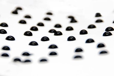 Beautiful drops of black ink lie on white paper on a black background in macro