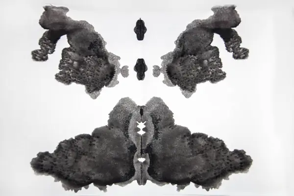Beyaz arkaplanda siyah mürekkep Rorschach Testi 'nde süslü bir desen oluşturulur.