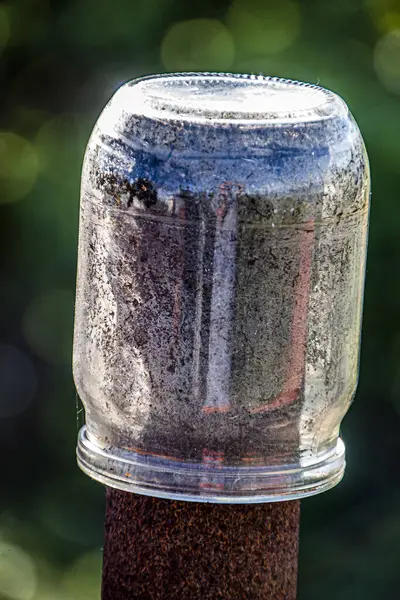 Glass jar hanging on a rusty pole close-up