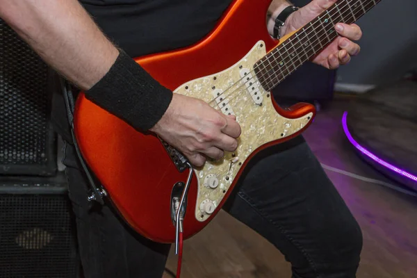 Guitarist playing a red electric guitar