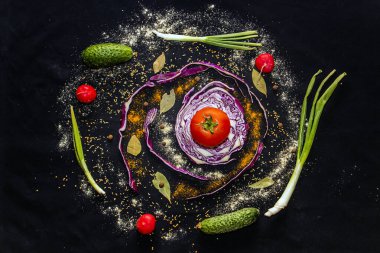 Siyah arka planda baharatları olan çok renkli sebzeler.