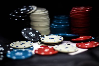 Birçok renkli poker fişi siyah bir arkaplanda bir yığın içinde yatıyor.