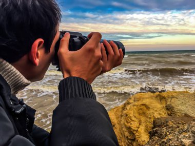Fotoğrafçı büyük bir objektifle deniz ufkunun fotoğrafını çekiyor.