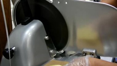 Bir kadın lezzetli bir peyniri dilimleyiciyle keser.