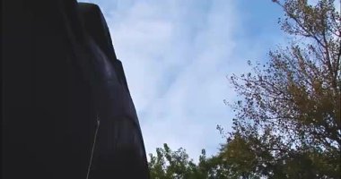 Bir adam yavaş çekimde büyük bir traktör lastiğinin içinden park tarzında 360 derece dönüş yapıyor.