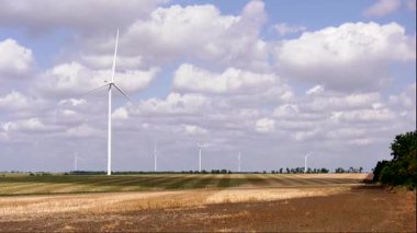 Büyük beyaz yel değirmenleri yazın bir tarlada durur.