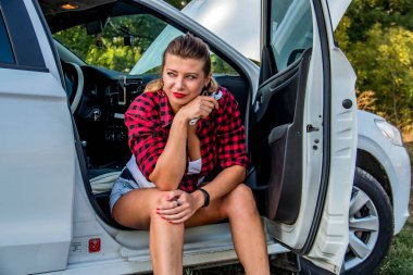 Kapısı açık beyaz bir arabada oturan güzel kız.