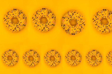 Donut deseni. Sarı arka planda renkli çörekler, donutlar ve çikolatalar. Donut ve krema. asgari kavram.