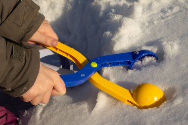 Kışın çocuğun eli karla oynuyor.