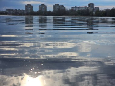 Güneşli bir günde nehirden şehre manzara, gökyüzü, su, bulutlar, güneş, yansıma, su yüzeyi