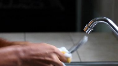 Erkek elleri mutfakta sabunlu sünger ve suyla büyük kaşığı yıkayıp duruluyor.