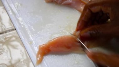 Eller çiğ tavuk göğsünü bıçakla parçalara ayırıyor.