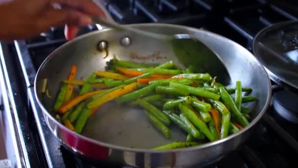 これは ストーブのフライパンでスプーンで調理し ひも豆をかき混ぜてカットしたビデオショットです — ストック動画