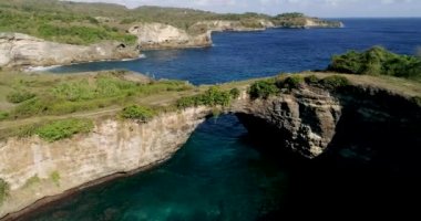 Endonezya 'da, Nusa Penida' da okyanusun üzerinde kaya kemerinin üzerinden uç. Yüksek kalite 4K görüntü. 4K Havacılık