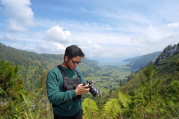 Genç fotoğrafçı kameraya bakıyor. Manzarası çok güzel. Dijital kameralı erkek fotoğrafçı.