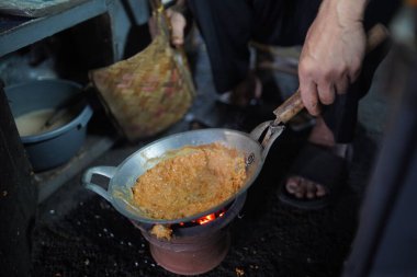 Satıcı, kömür ocağı olan küçük bir tavada yumurta kabuğu veya kerak telor pişiriyor. Kerak Telor, ördek yumurtasıyla hindistan cevizi rendelenmiş pirinç karıştırılmış geleneksel bir jakarta yemeğidir..