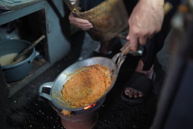 Satıcı, kömür ocağı olan küçük bir tavada yumurta kabuğu veya kerak telor pişiriyor. Kerak Telor, ördek yumurtasıyla hindistan cevizi rendelenmiş pirinç karıştırılmış geleneksel bir jakarta yemeğidir..