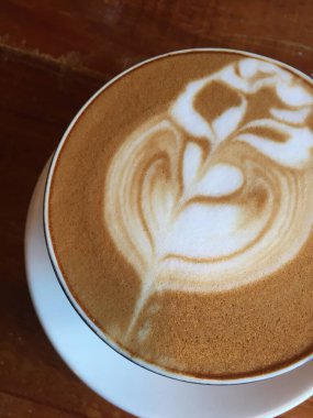 Close-up photo of a cappuccino with latte art in a ceramic cup on a concrete table. The latte art design resembles a rosetta. clipart