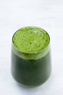 Canlı yeşil bir smoothie ya da köpüklü bir katmanla kaplanmış temiz bir bardaktaki meyve suyu. İçkiler taze ve davetkar görünüyor, köpüğünde küçük yeşil benekler var..