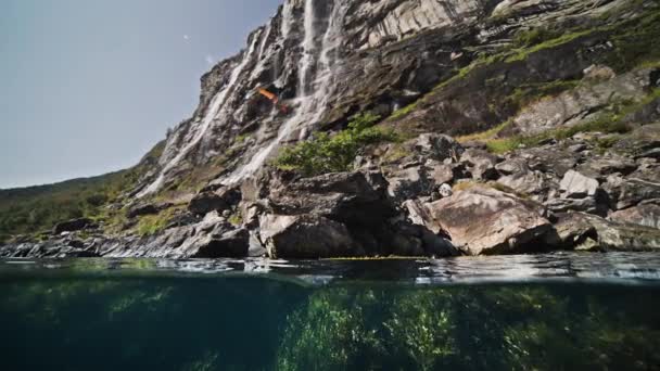 对峡湾的过低的一击 太阳耀斑在水下岩石上跳舞 瀑布从高高的悬崖上瀑布而下 高质量的4K镜头 — 图库视频影像