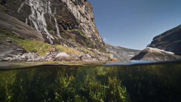 フィヨルドのオーバーアンダーシュート 太陽のフレアは雑草で覆われた底で踊る 崖から滝カスケード高品質4K映像 — ストック動画