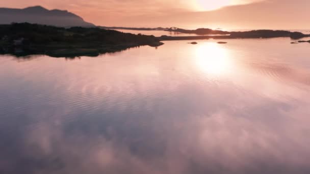 大西洋の道路で結ばれた群島の上の夕日の空中ビュー 穏やかな水から反射した明るい太陽の光 スローモーション パンを残しました 高品質4K映像 — ストック動画