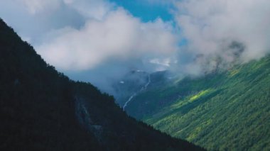 Aerial view of the wide green valley. White fluffy clouds float above. Slow-motion, hyperlapse. High quality 4k footage