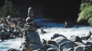 A small stone cairn on the riverbank. Loop video. High-quality 4k footage