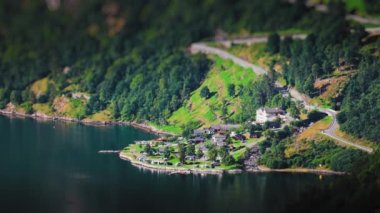 Geiranger fiyordunun üstündeki dik dağ yolunda trafik vardı. Fiyort kıyısında bir kamp alanı var. Hava görüntüsü. Tilt-shift videosu. Yüksek kalite 4K görüntü.