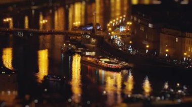 Gece Prag şehir merkezindeki rıhtımdaki trafik ve köprülerin hava görüntüsü. Sokak lambaları nehre yansıyor. Yavaş çekim, sola çevir, yana kaydır. Yüksek kalite 4K görüntü