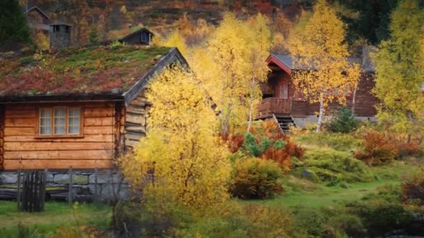 山のふもとの秋の風景の中には 石造りの土台と土製の屋根を持ついくつかの小さな木造キャビンがあります スローモーション パンを残しました 高品質4K映像 — ストック動画