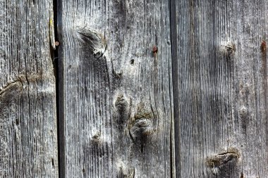 Görünür tahılları, düğümleri ve paslı çivileri olan eski ahşap kalaslara yakın çekim. Görünüşte gri ve yıpranmış.
