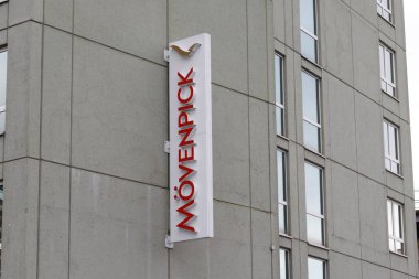 Nuremberg, Almanya - 25 Mayıs 2025: Kırmızıyla bir Movenpick otel tabelası, görünür pencereleri olan gri beton bir binaya dikey olarak monte edilmiş.