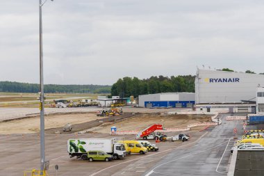 Nuremberg, Almanya - 25 Mayıs 2025: İnşaat, servis araçları ve bulutlu bir gökyüzü altında bir Ryanair binası ile havaalanı sahnesi.