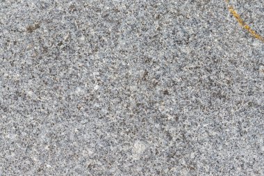 Yakından bakıldığında lekeli bir yüzey ortaya çıkar, çoğunlukla gri, farklı tonlar ve dokular ile. Sağ üstte turuncu bir çizgi var..