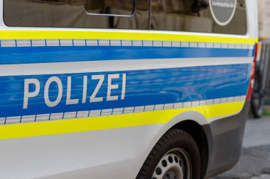 Münih, Almanya - 14 Haziran 2025: Mavi ve sarı çizgili beyaz bir polis minibüsü ve beyaz harfli 