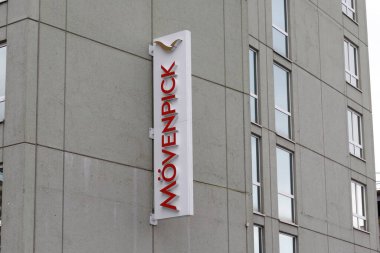 Nuremberg, Almanya - 25 Mayıs 2025: Kırmızıyla bir Movenpick otel tabelası, görünür pencereleri olan gri beton bir binaya dikey olarak monte edilmiş.